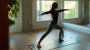 A woman is practicing yoga in a room with a large window.